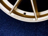 A close-up of a gold alloy wheel rim featuring embossed text 