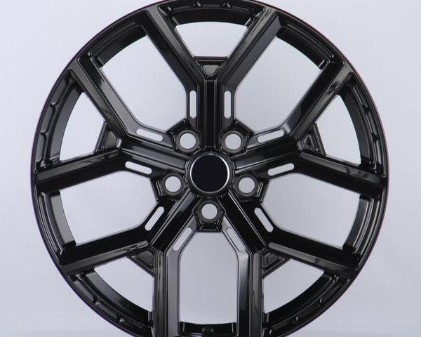 Black, glossy, multi-spoke alloy wheel; resting upright in a well-lit studio setting; casting a slight shadow on the white background.