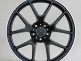 A black alloy wheel with a Mercedes-Benz logo is centered against a light background. It has a sleek multi-spoke design and displays the text 
