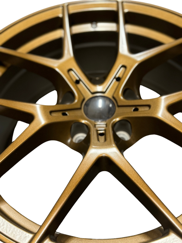 A bronze alloy car wheel, featuring a multi-spoke design with a central hub, is displayed against a plain white background.