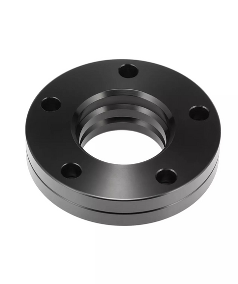 A black metal flange features five bolt holes and a central threaded opening, lying stationary against a plain white background.