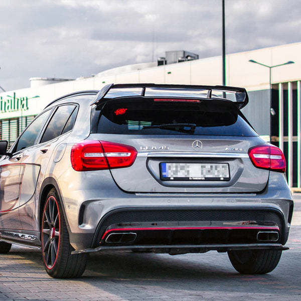 A silver Mercedes-Benz A45 AMG parked in a shopping center lot, featuring spoiler and red accents. Background shows buildings with "europa centralna" signage and cloudy sky.