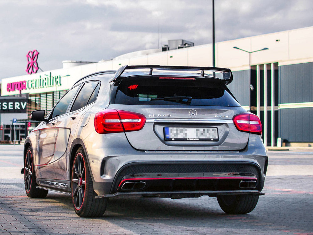 A silver Mercedes-Benz A45 AMG parked in a shopping center lot, featuring spoiler and red accents. Background shows buildings with "europa centralna" signage and cloudy sky.
