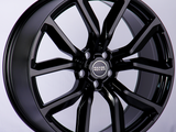 A glossy black wheel rim features a multi-spoke design with a central cap labeled 