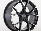 A black and silver Audi wheel rim with a five-spoke design is displayed against a plain white background. The Audi logo is centered on the wheel hub.