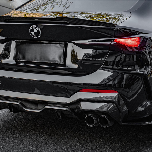 A sleek black BMW car is parked, showcasing its rear with dual exhausts and vibrant taillights, in a parking lot alongside other vehicles.