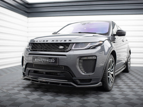 A gray Range Rover is parked in a garage with checkered flooring. The front bumper features a "#Maxtonized" license plate. The vehicle is positioned in front of white panel walls.
