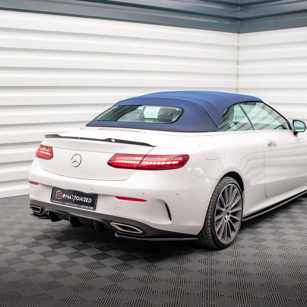A white convertible car with a blue roof is parked in a modern, checker-patterned showroom. The license plate reads “@MA_TONIZED.”