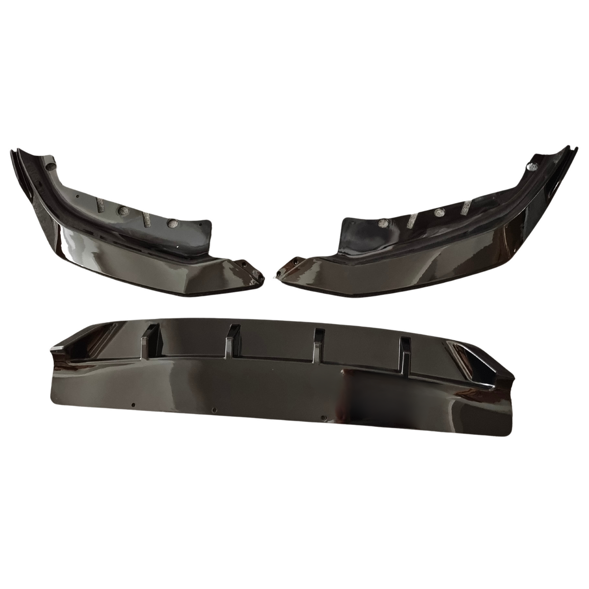 Three glossy black car bumper components arranged on a white background, including two side pieces with mounting holes and one central piece with vertical fins.