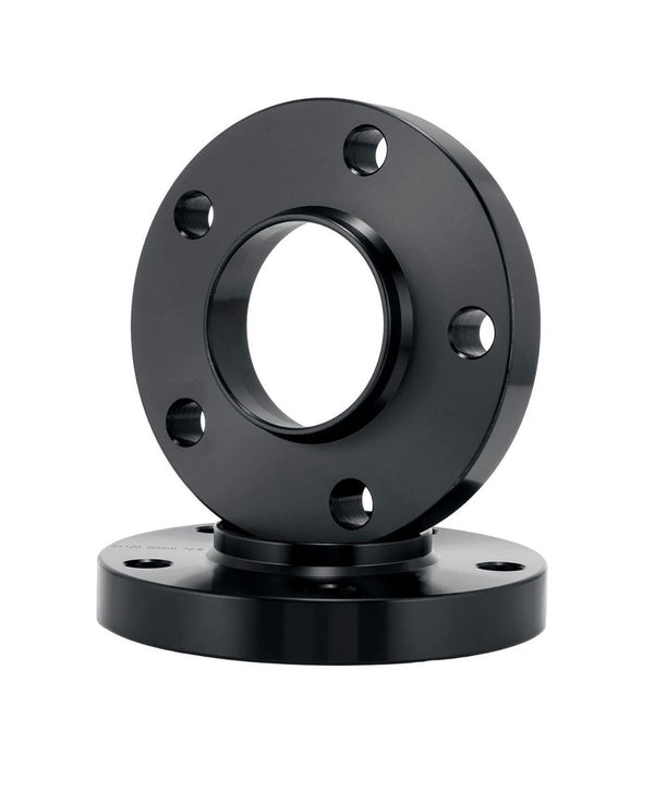 A black metal flange with several bolt holes is positioned upright against a second flange lying flat. The smooth, reflective surfaces are highlighted in a plain white setting.