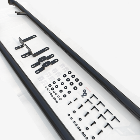 Two long black metal bars lie on a white surface, accompanied by various brackets, washers, screws, nuts, and other hardware components arranged systematically.