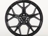 A black alloy wheel with a multi-spoke design, featuring the Mercedes-Benz logo at the center and 