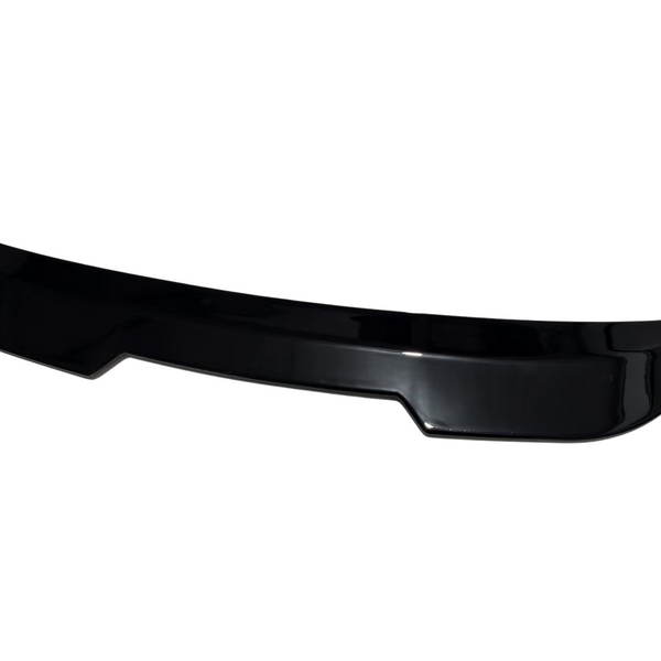 A glossy black car spoiler, segmented with slight curves, rests isolated on a plain white background.