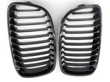Two glossy black car grilles with horizontal slats are placed side by side against a plain white background.