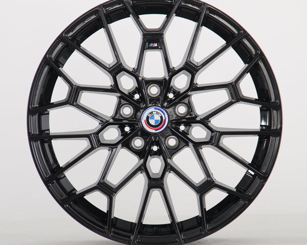 A black alloy wheel with intricate spokes is displayed, featuring a central BMW emblem. The wheel stands vertically against a plain white background.