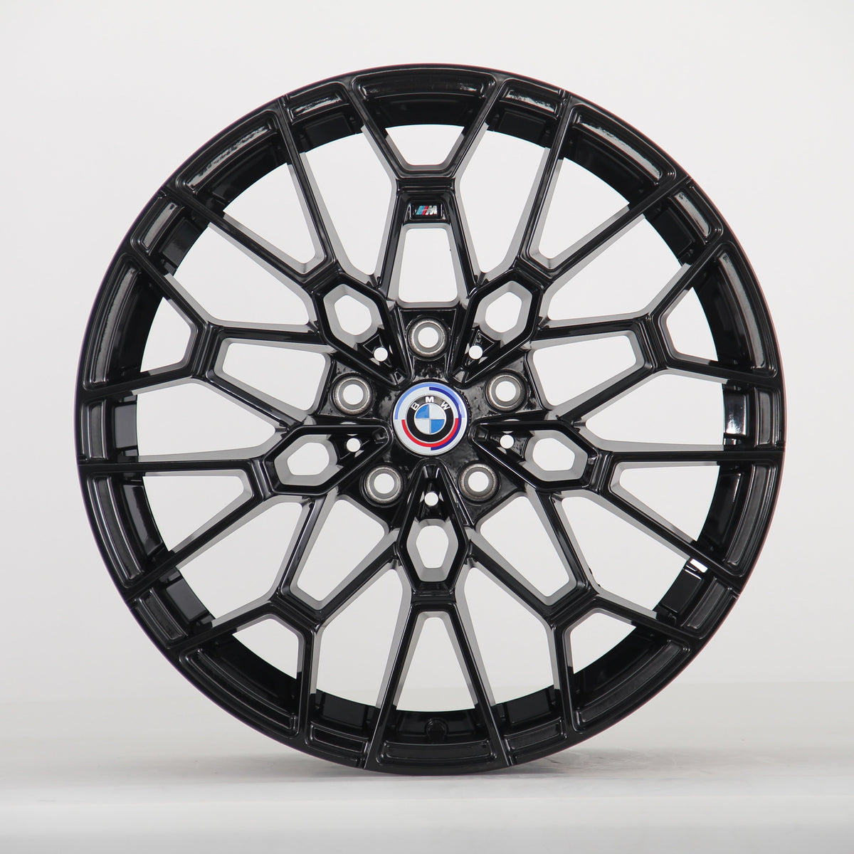 A black alloy wheel with intricate spokes is displayed, featuring a central BMW emblem. The wheel stands vertically against a plain white background.