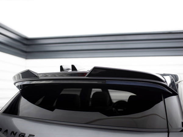 A silver car with a sleek roof spoiler is parked in a clean, modern garage. Text on the back reads "RANGE."