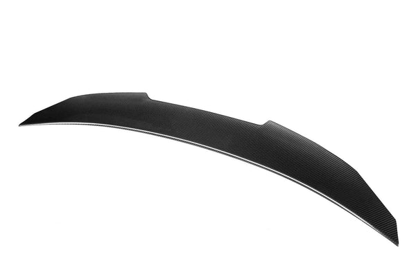 A sleek, curved black car spoiler lies against a plain white background, showcasing its aerodynamic design and textured surface.
