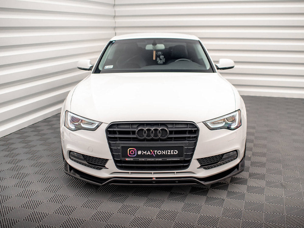 A white Audi car is parked in a patterned indoor space with textured floors and walls. The front license plate displays "#MAXTONIZED."