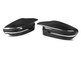 Two carbon fiber side mirror covers sit on a white background, showcasing a sleek, glossy, and textured design, emphasizing an automobile accessory concept.