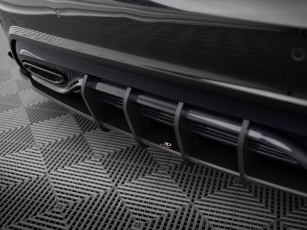 A sleek car diffuser with vertical slats at the rear, positioned above a textured, grid-patterned floor.