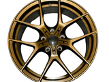 A bronze-colored alloy wheel with a five double-spoke design is positioned against a plain white background, showcasing intricate detailing and a central hub.