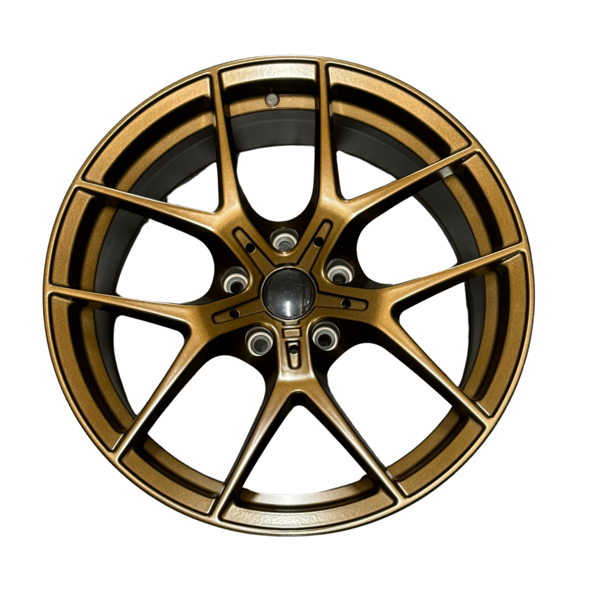 A bronze-colored alloy wheel with a five double-spoke design is positioned against a plain white background, showcasing intricate detailing and a central hub.