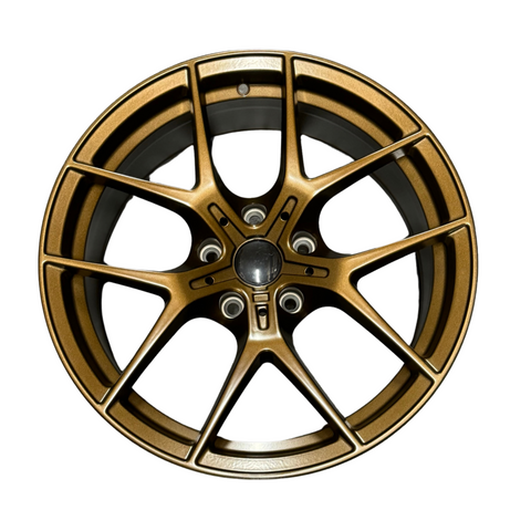 A bronze-colored alloy wheel with a five double-spoke design is positioned against a plain white background, showcasing intricate detailing and a central hub.