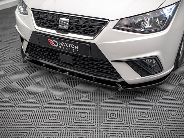 A white car's front end, featuring a black grille and "MAXTON design" text, parked on a patterned grey floor.