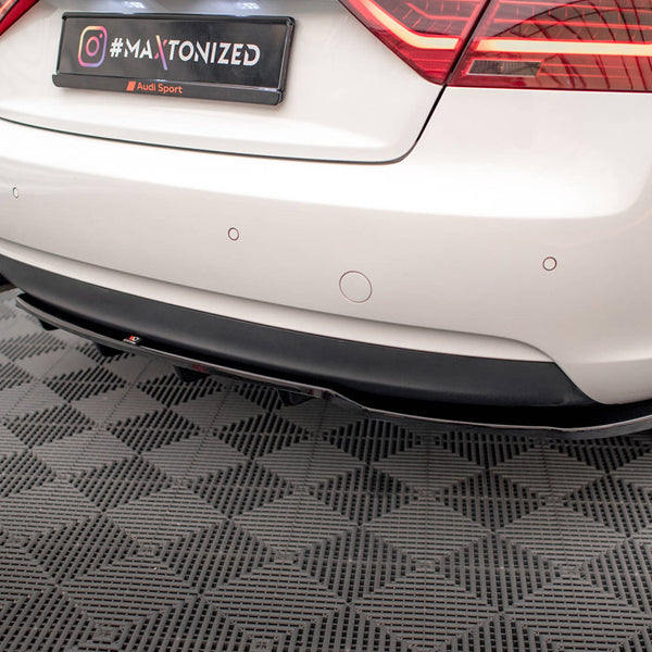 The rear of a white car with a visible black diffuser and dual exhausts, features a "#MAXTONIZED" tag and Audi branding, parked in a garage with checkered flooring.