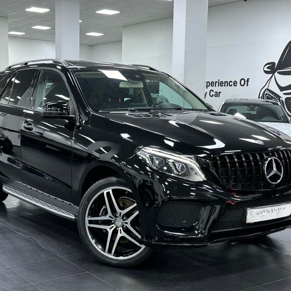 A black SUV is parked indoors, featuring a sleek design and alloy wheels. The setting is a showroom with white walls and a car illustration. Text on the wall reads, "Experience Of Luxury Car."