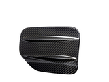 A carbon fiber automotive vent cover, angled with diagonal slats, displayed against a plain white background, emphasizing its glossy, textured surface.