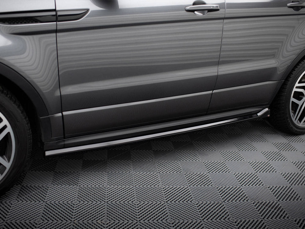 A grey SUV side, with polished metallic running boards, is parked on a patterned floor. The vehicle has clean lines and sleek wheel rims, indicating a modern design.