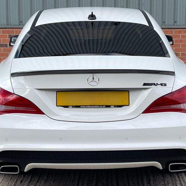 A white Mercedes-Benz AMG car is parked, featuring dual exhausts and tinted windows, against a backdrop of red brick and corrugated metal. Text: "www.mdscarsales.co.uk".