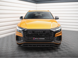 Yellow Audi SUV parked inside a bright, white-paneled garage with black flooring. The front grille is prominent. Visible text: 