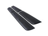 Long black car side skirts lie parallel on a plain white background, featuring subtle grooves and slightly raised sections for attachment or aerodynamic purposes.