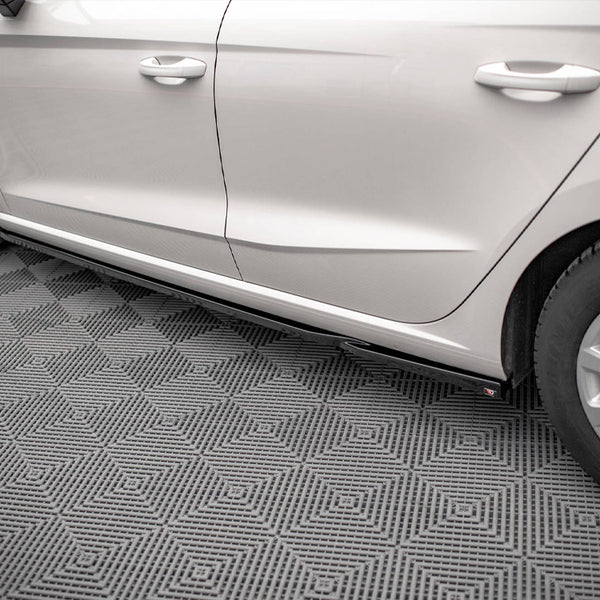 Car parked on a textured gray floor, showing the side doors and tires, with a visible step below the doors. No text is present.