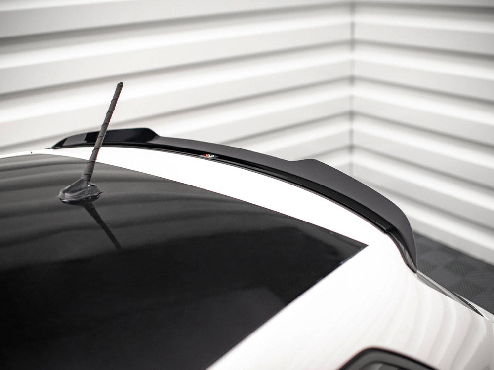 A car roof with a black roof spoiler and aerial, set in a corner with white horizontal wall panels.