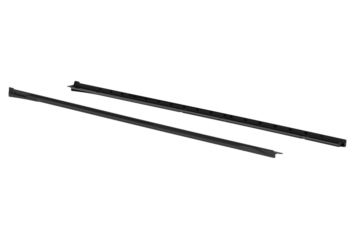 Two long, black plastic rails are placed parallel to each other on a white background, each with a series of evenly spaced grooves.