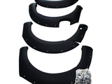 Four black fender flares with rivets lay arranged in a descending order, accompanied by a clear plastic bag filled with bolts and screws on a white background.