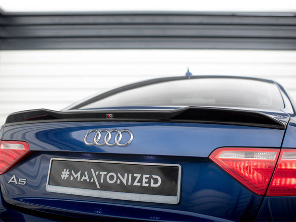 A blue Audi A5 features a black spoiler on its rear, parked in front of a striped garage door. The license plate reads "#MAXTONIZED".
