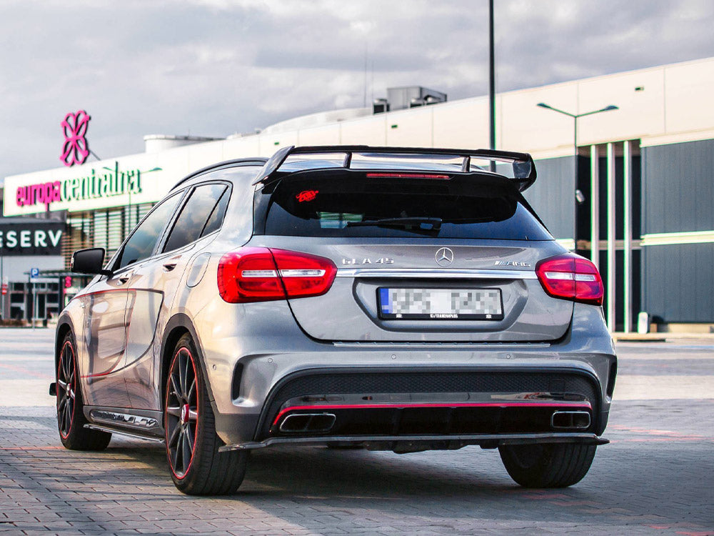 A silver car with a prominent rear spoiler is parked on a paved area. Logos read "CLA 45" and "AMG." The background features a building labeled "europa centralna."