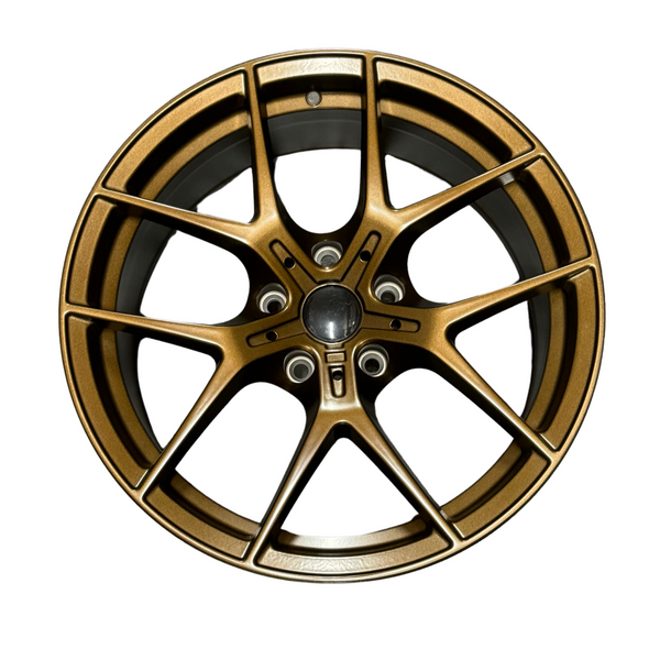 A bronze alloy car wheel rim with a multi-spoke design is displayed against a plain white background. The rim features a central hub and five bolt holes.