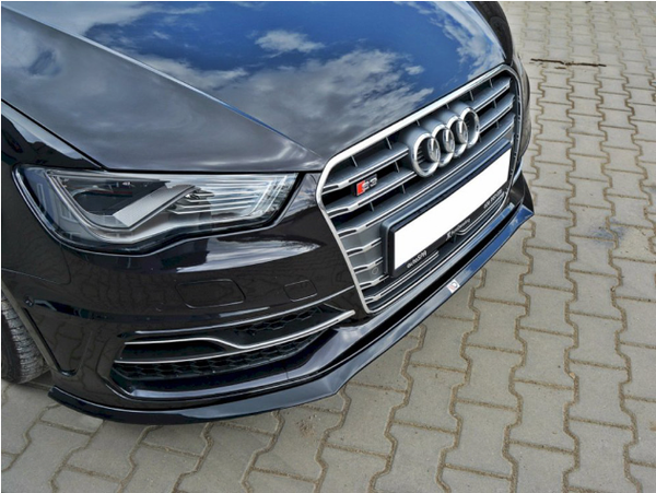A black car front features a stylized grille with four rings and an "S3" badge, reflecting clouds. The vehicle is parked on a block paved surface.