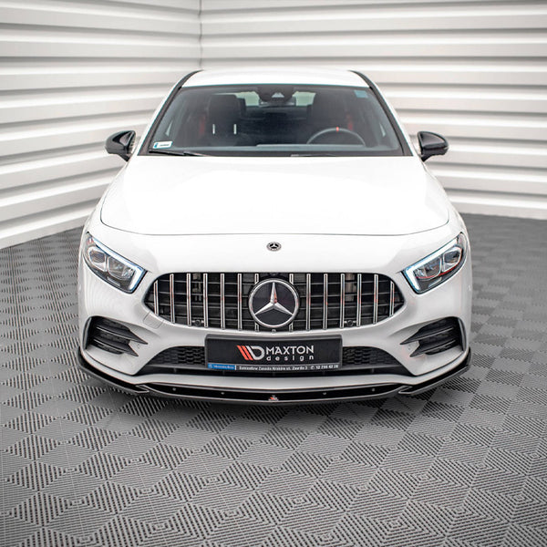 A white car is parked inside a patterned room. It features a prominent front grille with a logo and has text: “MAXTON DESIGN.” The background has textured walls and floor.