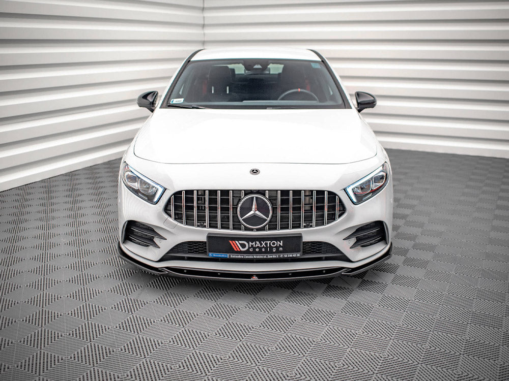 A white car is parked inside a patterned room. It features a prominent front grille with a logo and has text: “MAXTON DESIGN.” The background has textured walls and floor.