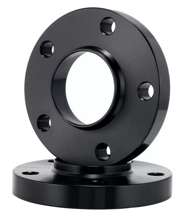 A black metal flange with multiple bolt holes is standing vertically on another similar flange in a studio setting, highlighting its circular shape and industrial design.