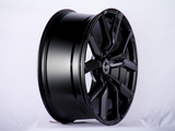 A shiny black alloy wheel, with 