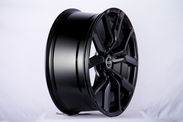 A shiny black alloy wheel, with "RANGE ROVER" text on the center cap, stands upright against a plain white backdrop.