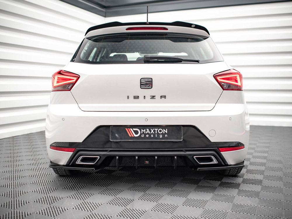 A white car is parked in a showroom. The rear features the text "IBIZA" and "MAXTON design," with distinct taillights and a sleek bumper. The room has checkered flooring.